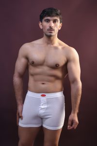 Portrait of a muscular man standing in a studio wearing white underwear.